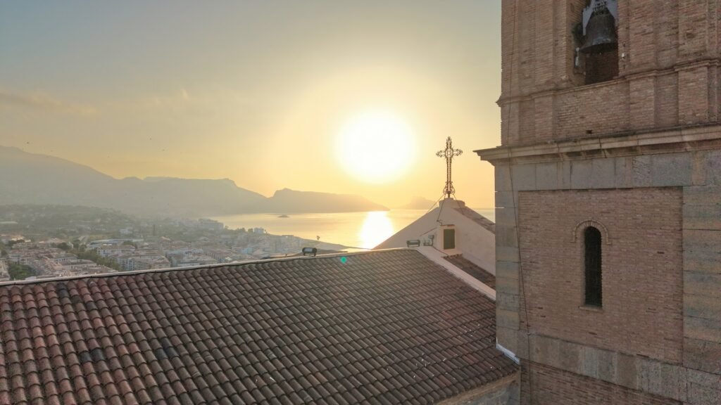 The bell tower of the church of Altea at sunrise, with the bay behind